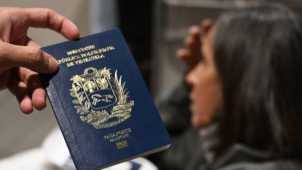 In Florida, Venezuelans stress over possible loss of TPS: NPR Hand holding Venezuelan passport, woman blurred background.