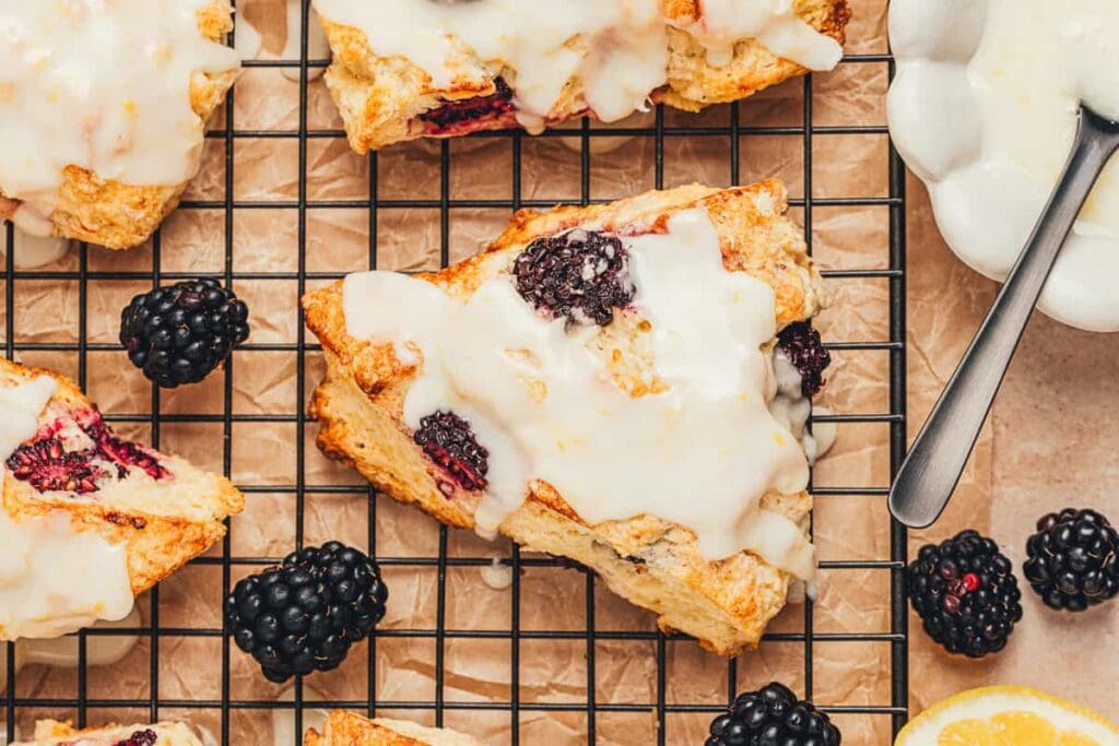 Glazed blackberry scones on a cooling rack.