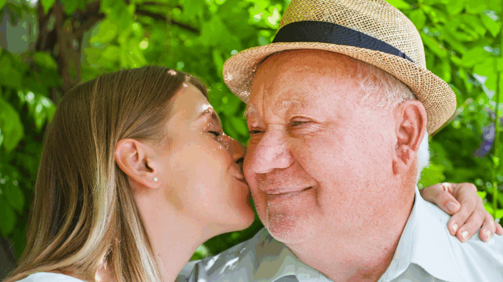 Adult child kissing her elderly dad on the cheek