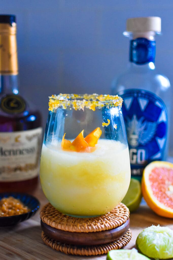 frozen Hennessy margarita in a glass rimmed with sugar and orange zest and garnished with an orange peel twist.
