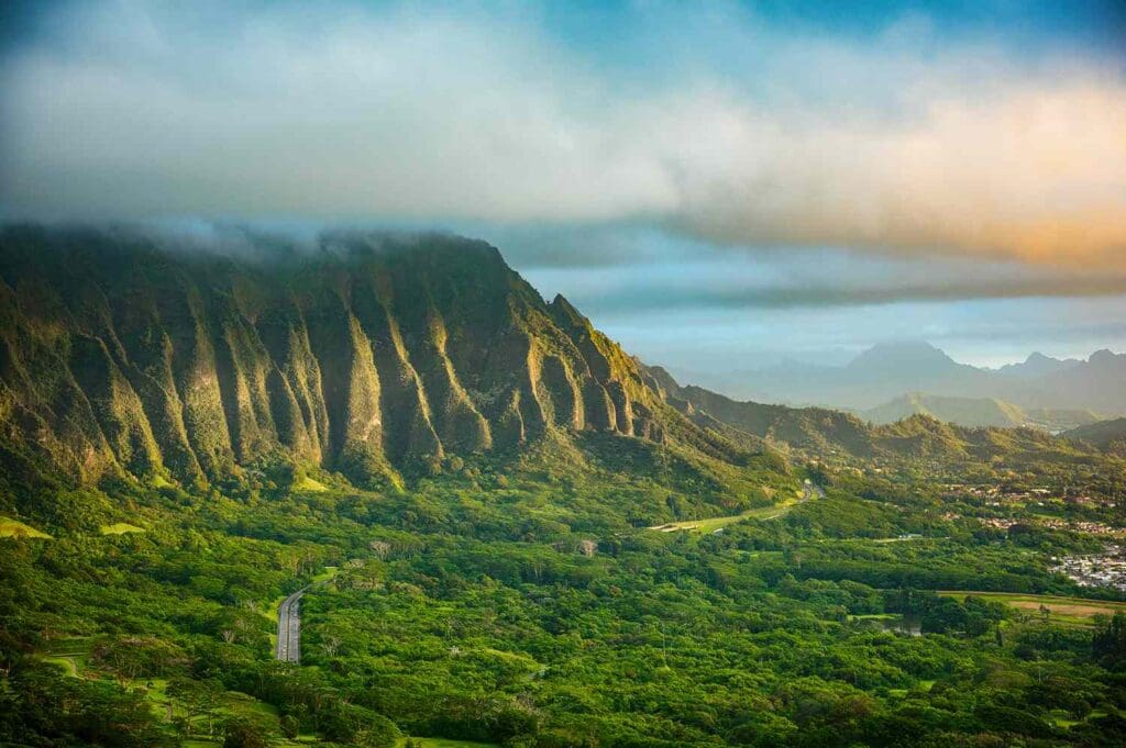 A scenic view of a lush valley with dramatic ridges and mountains in the background