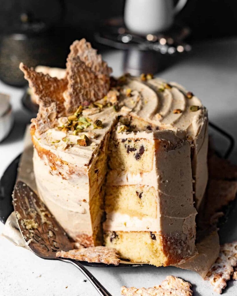 sliced cannoli cake on a cake plate topped with crushed cannoli shells.