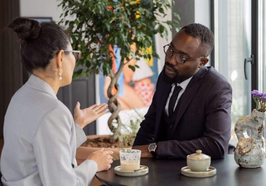 Two colleagues from different ethnic backgrounds chatting over coffee