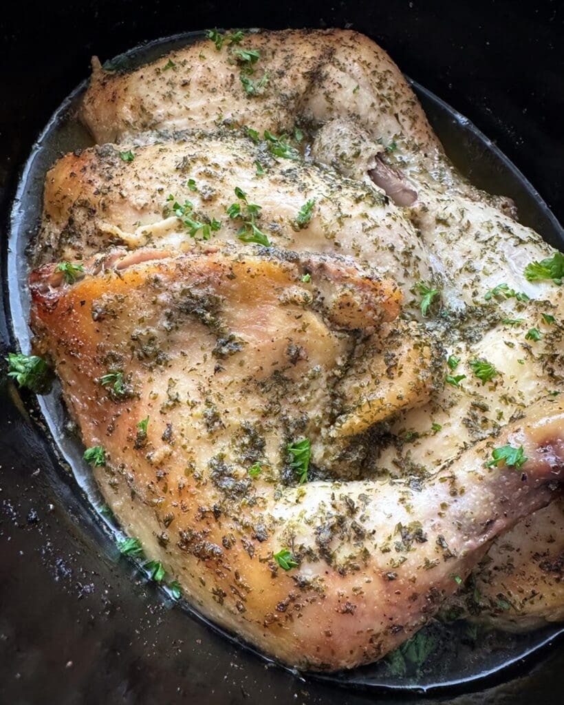 Herb-seasoned chicken cooking in slow cooker.
