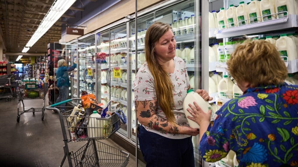 Women shopping for milk in grocery store.