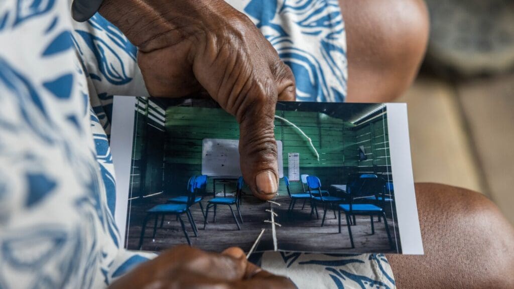 Hands holding photo of empty classroom.