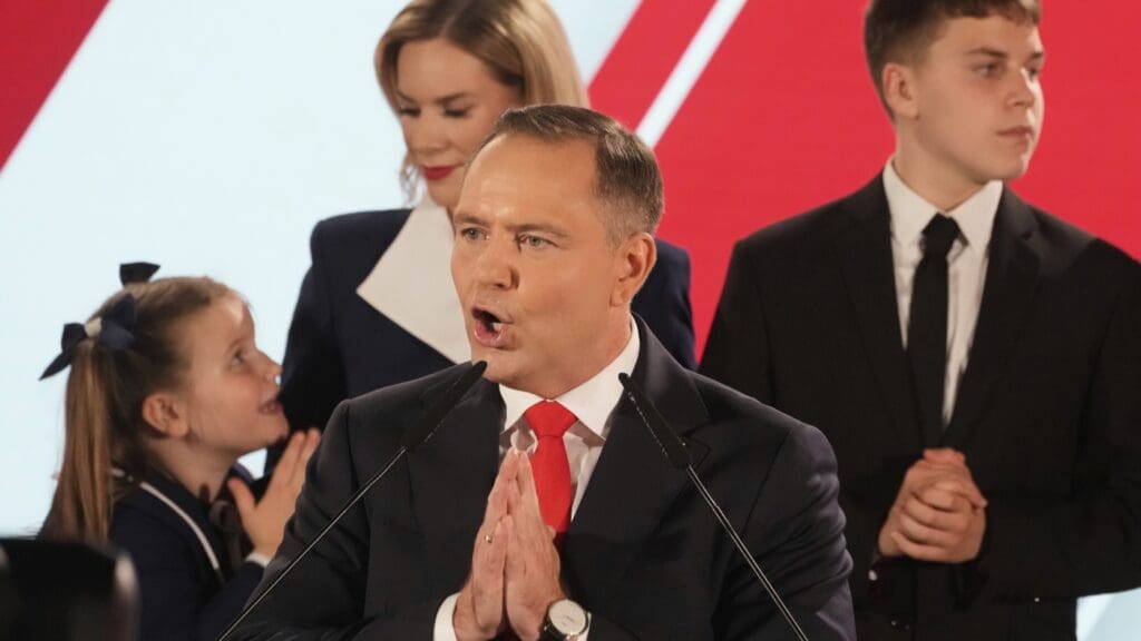 Man speaking at podium with family nearby.