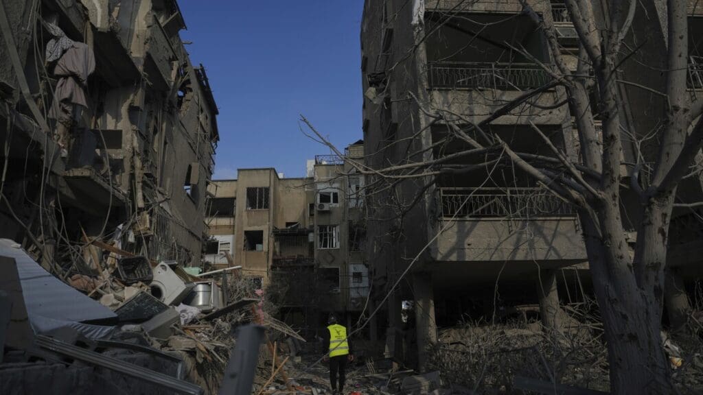 Damaged buildings with debris and lone person.
