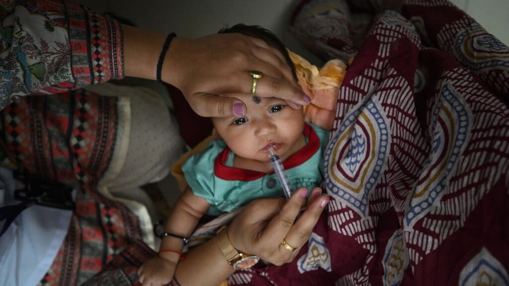 Baby receiving oral medication from caregiver.