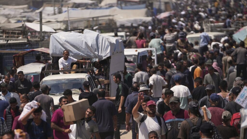 A minimum of 8 dead in capturing near Israeli and US-supported help websites in Gaza: NPR Crowded marketplace with people and vehicles.
