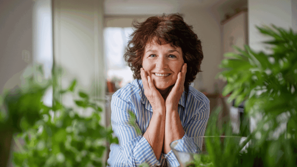 Happy senior woman sitting with hands on her face