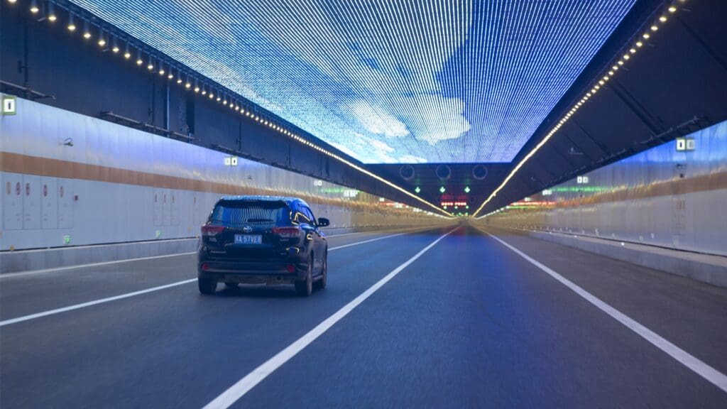 a car drives through a tunnel with an LED screen on the ceiling