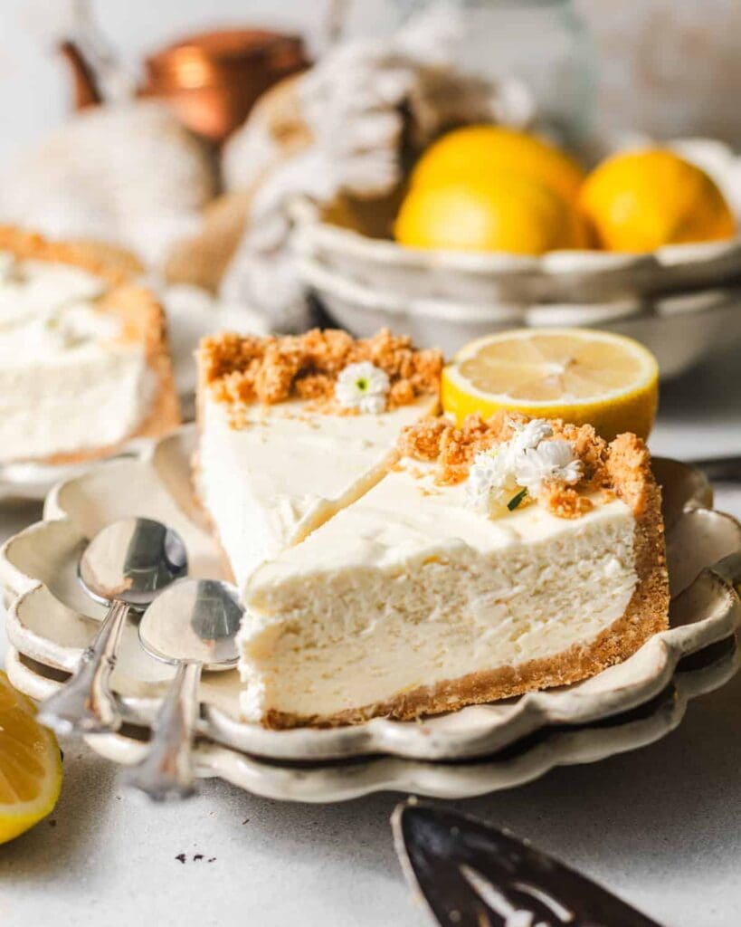 sliced lemon icebox pie on a plate with lemons and spoons.