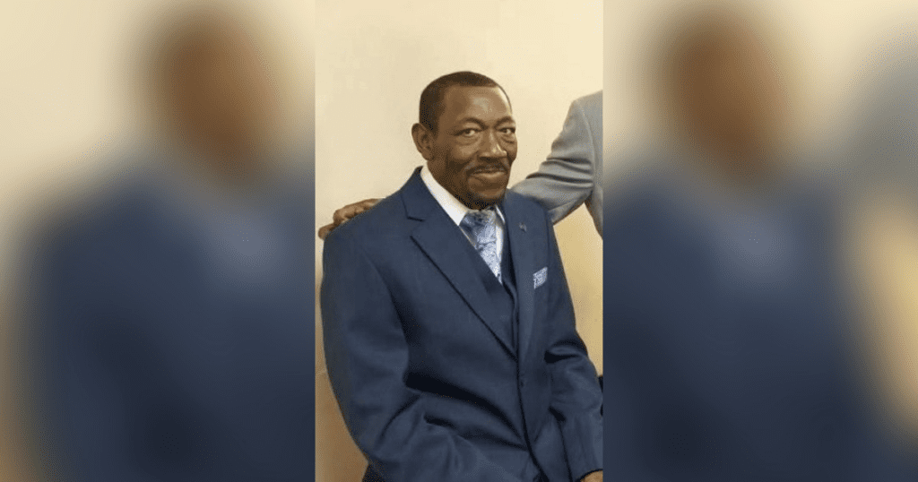 Man in blue suit sitting and smiling.