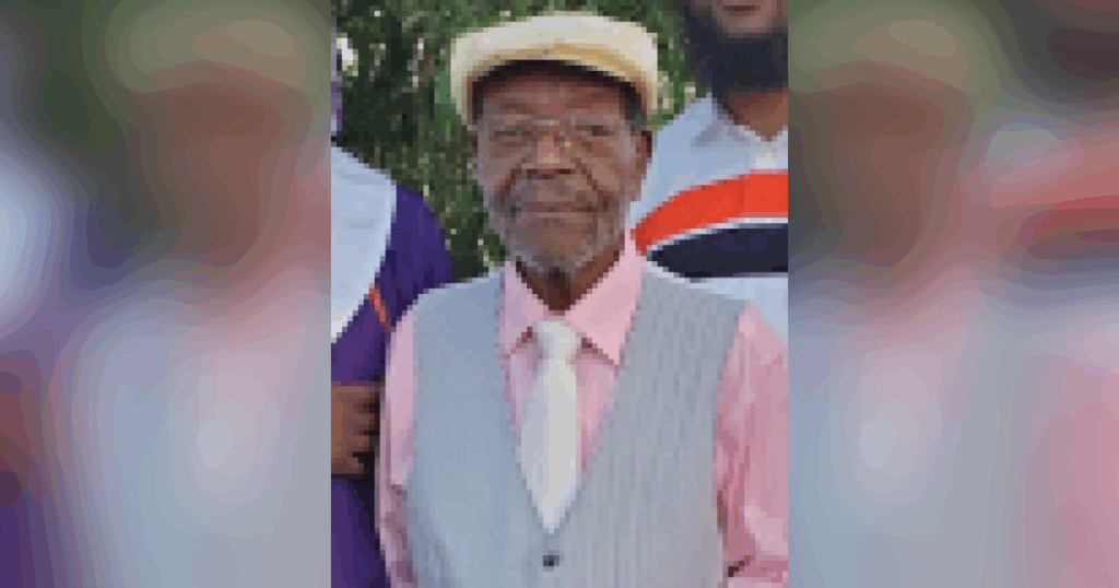 Elderly man in hat and vest outdoors.