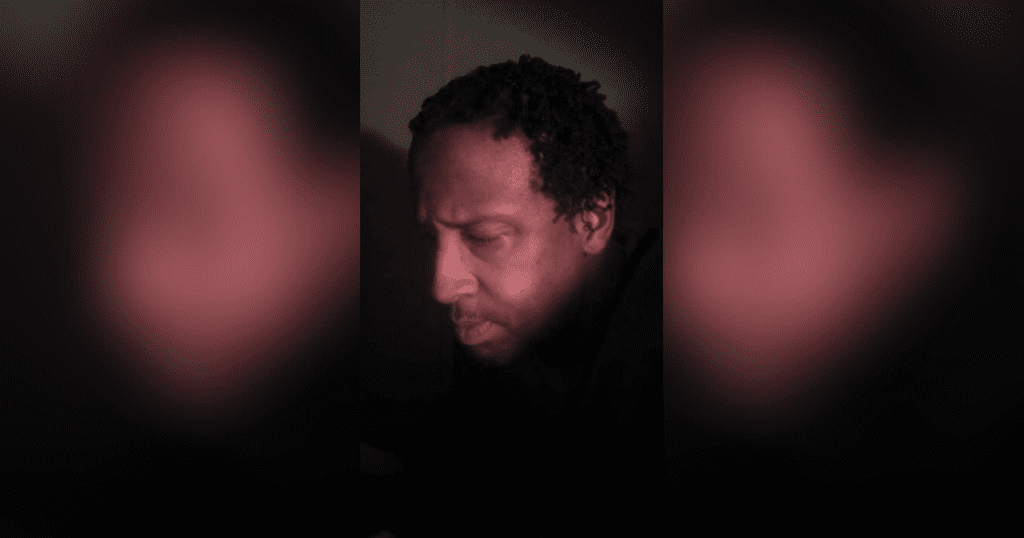 Man's face in dim lighting, focused expression.