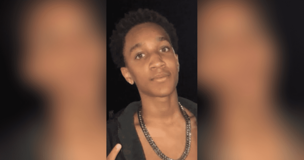 Young person wearing necklace, looking forward.