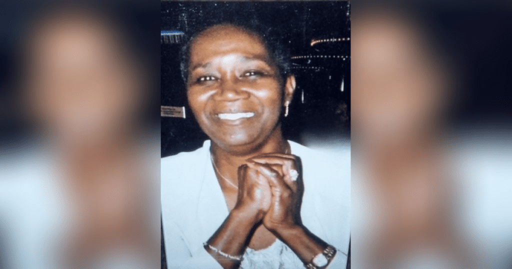 Smiling person with clasped hands in portrait.