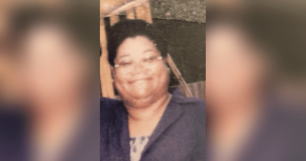Smiling person in a suit and glasses.