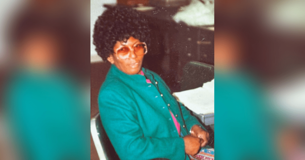 Person in green jacket seated indoors.