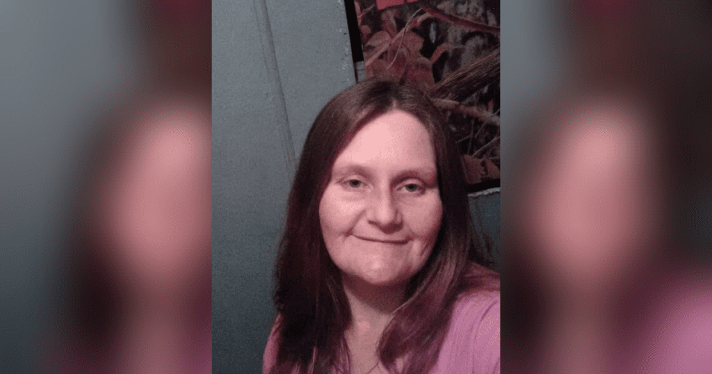 Woman smiling in casual indoor setting.