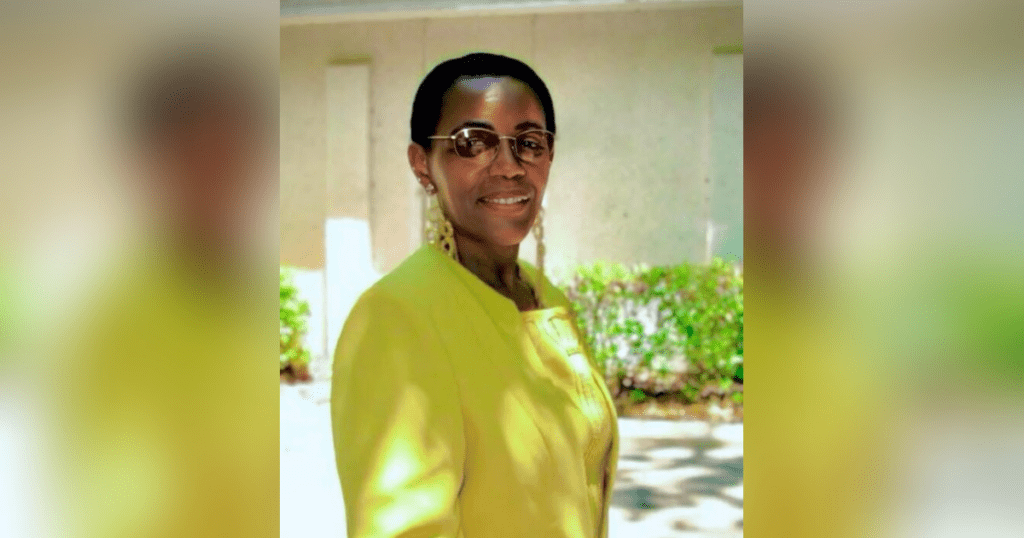 Person in yellow jacket outdoors, wearing sunglasses.