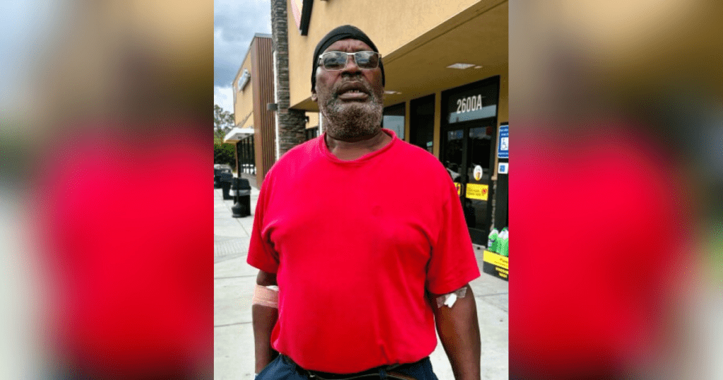 Man in red shirt outside a store.