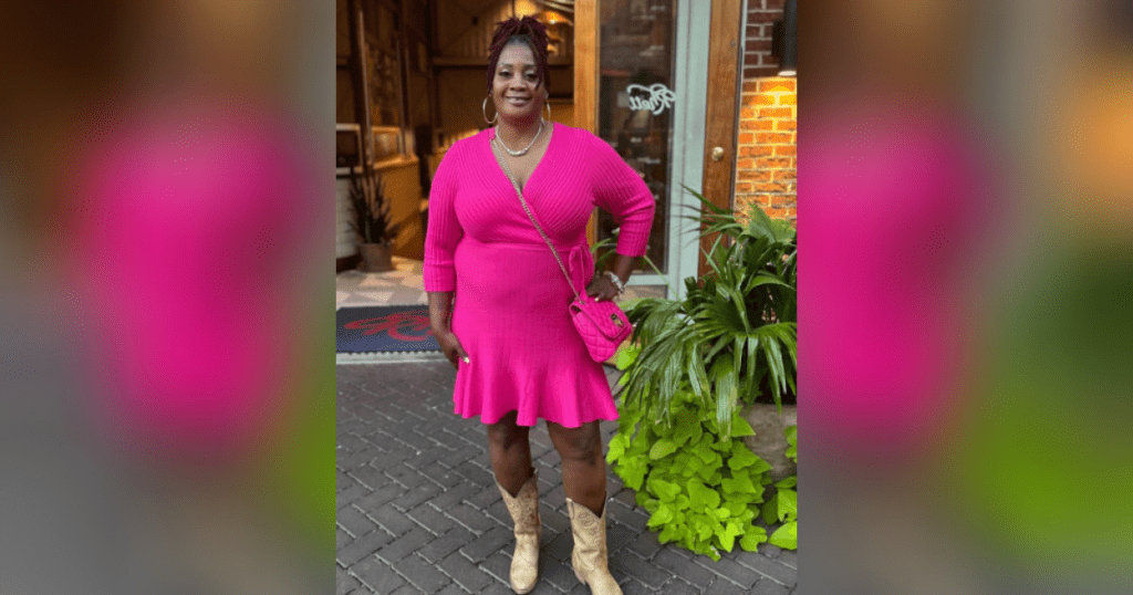 Woman in pink dress and boots outside.