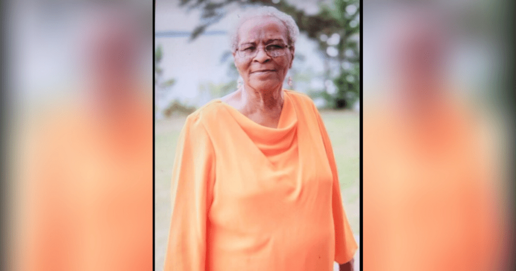 Elderly woman in orange dress outdoors.