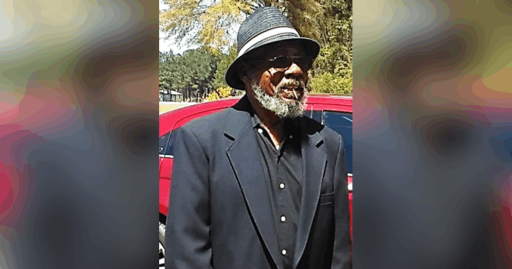 Man wearing hat and sunglasses outdoors.