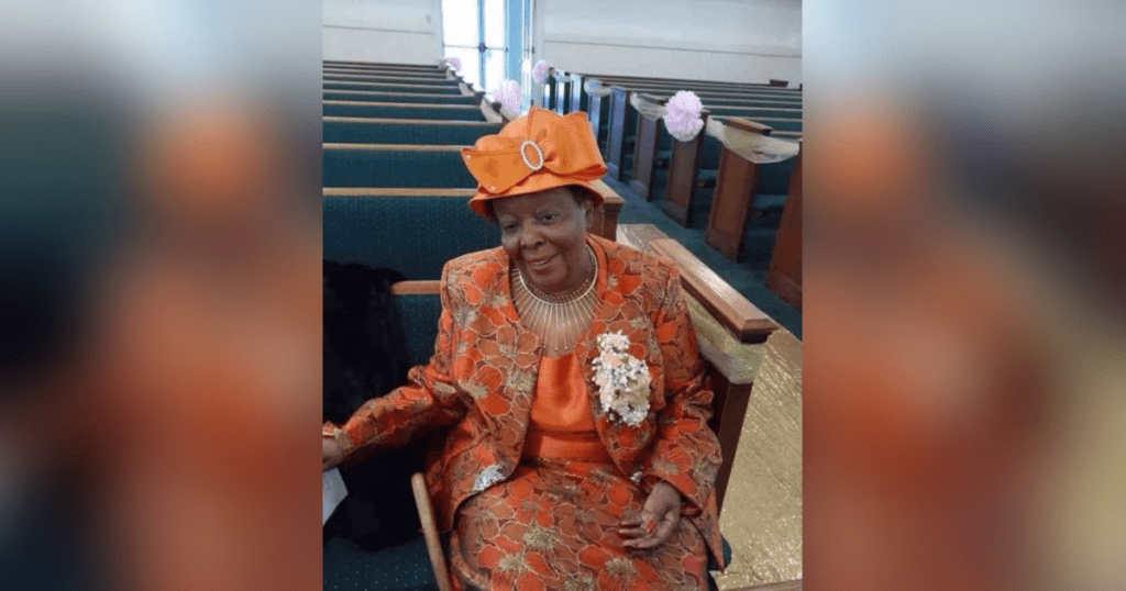 Woman in orange outfit sitting in church.