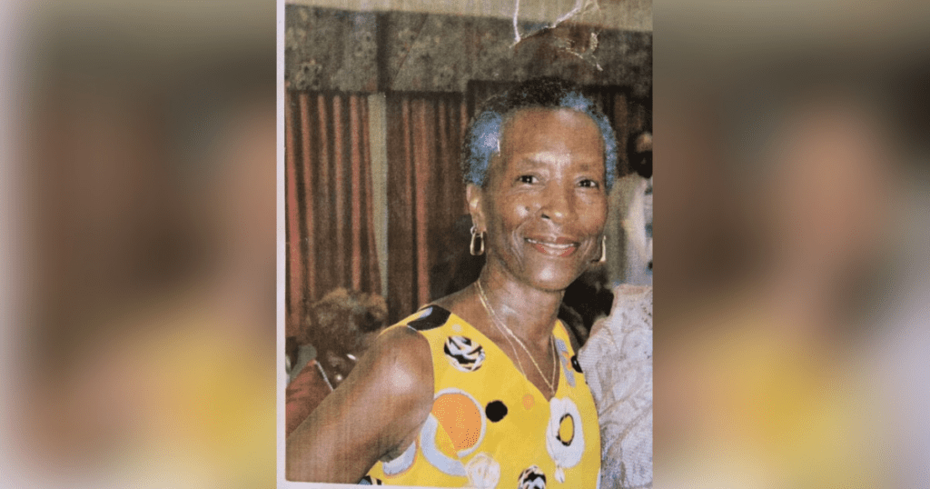 Smiling woman in colorful patterned dress.