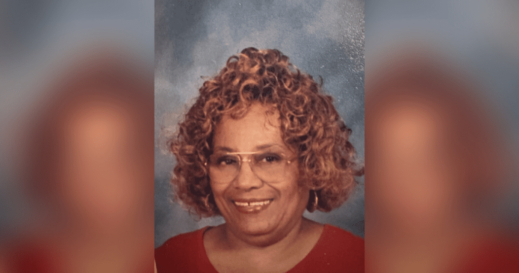 Smiling woman with curly hair and glasses.