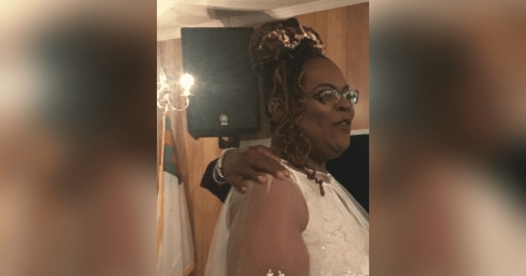 Smiling woman in white dress at event.