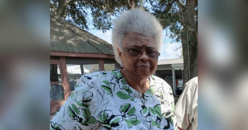 Elderly woman outdoors wearing floral blouse.