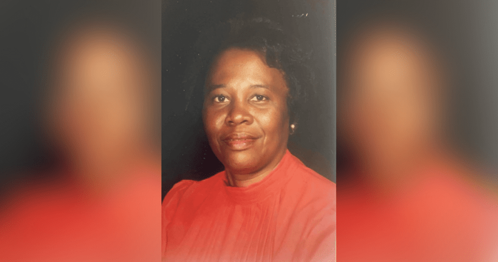 Woman in red blouse, smiling gently.
