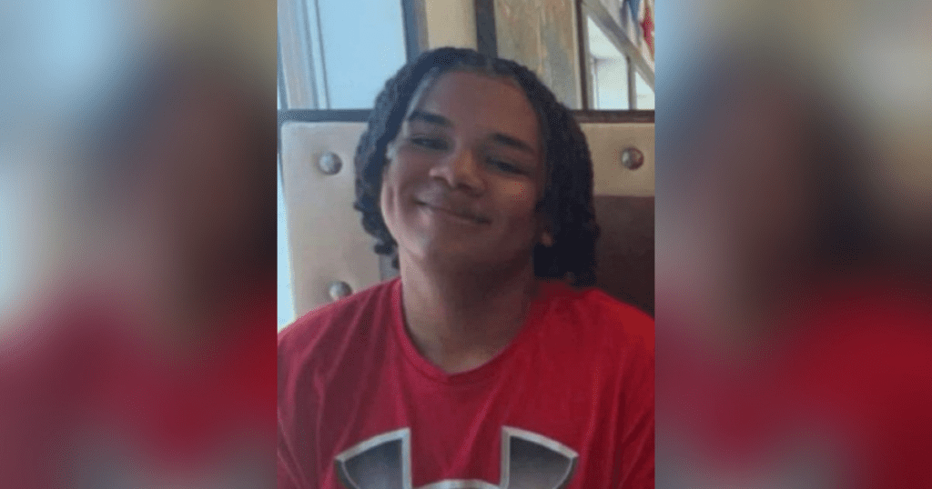 Smiling person wearing a red shirt indoors.