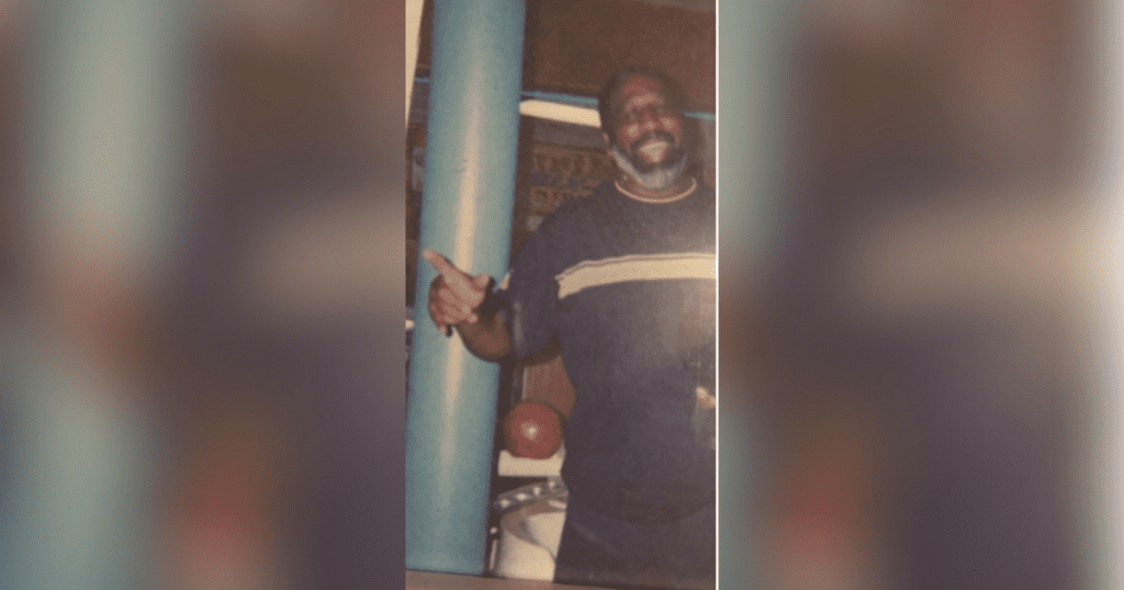 Smiling man posing with thumbs up gesture.