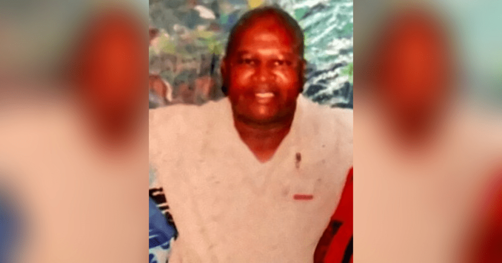 Smiling person in beige shirt, blurred background.