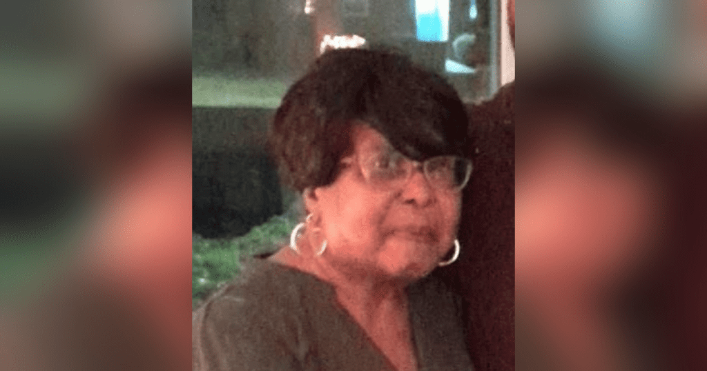 Elderly woman wearing glasses and earrings.