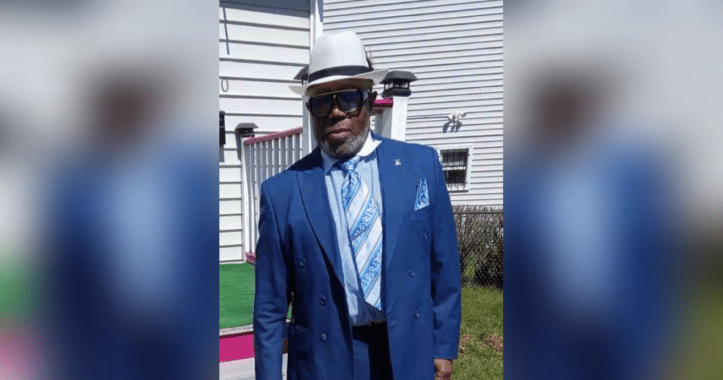 Man in blue suit and hat outdoors.