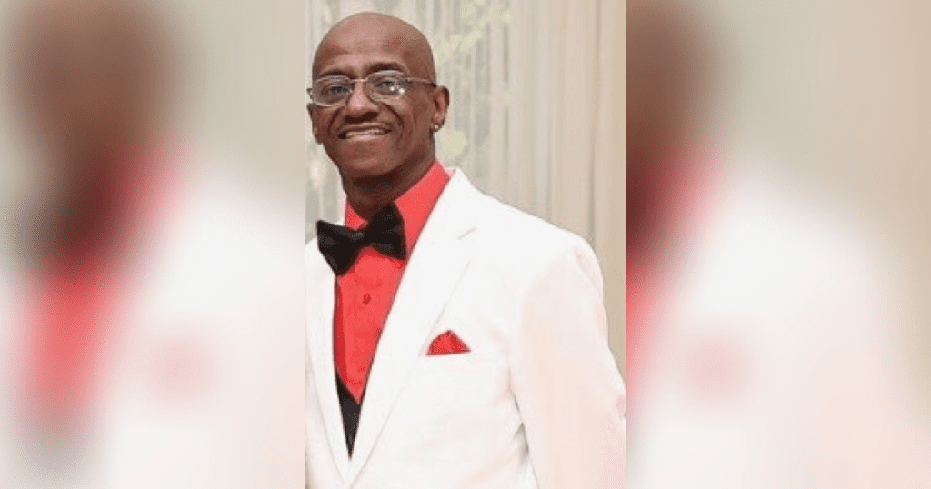 Man in white suit with red shirt.