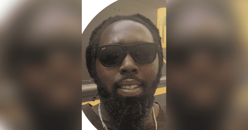 Man wearing sunglasses, smiling outdoors.