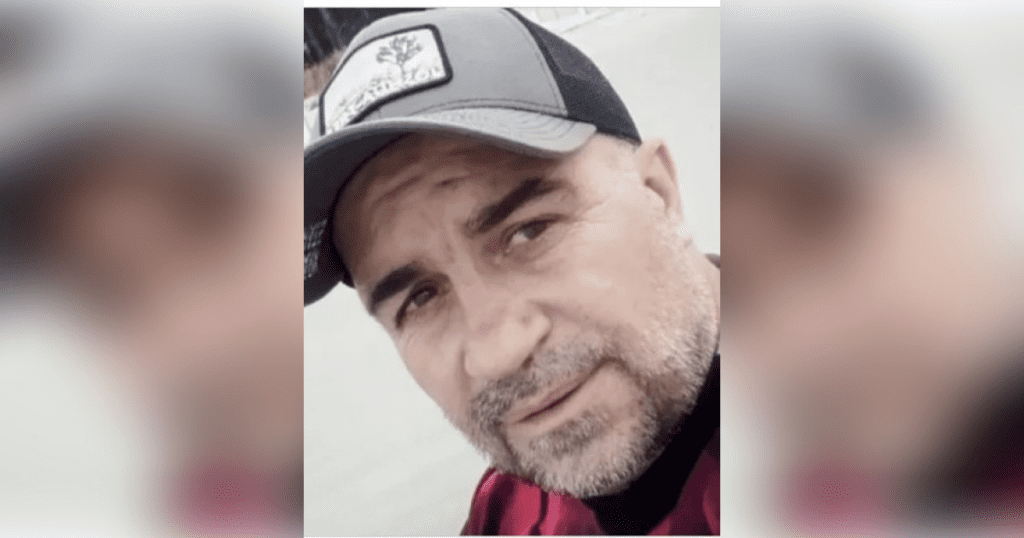 Man wearing cap and plaid shirt outdoors.