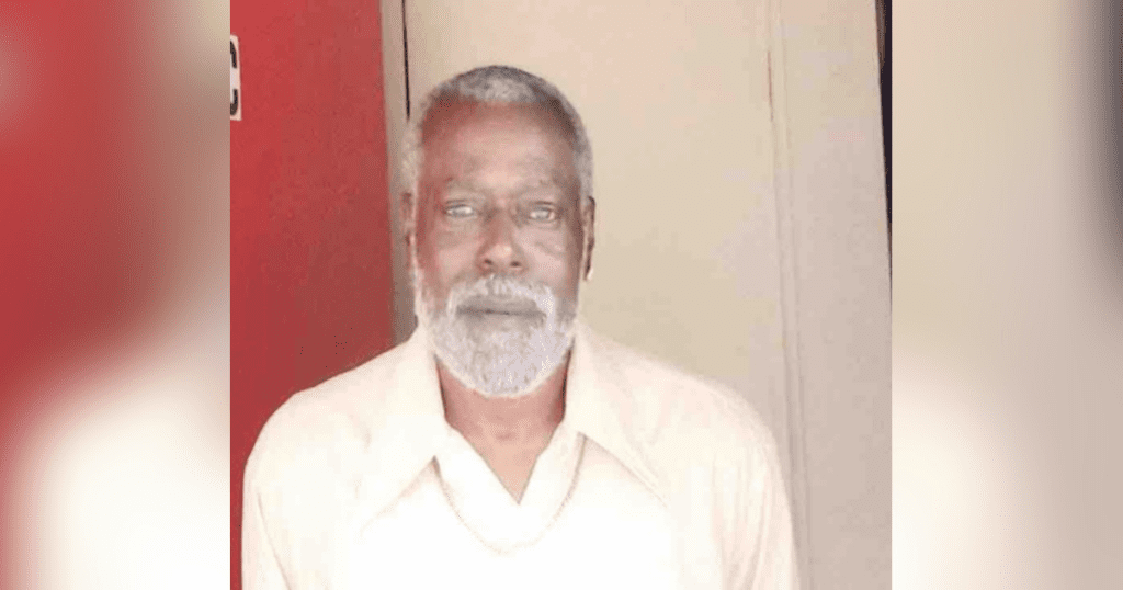 Elderly man with beard in white shirt.