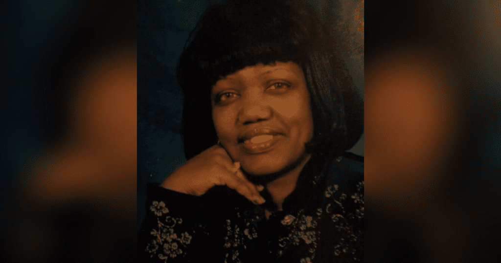 Smiling woman in black floral outfit.