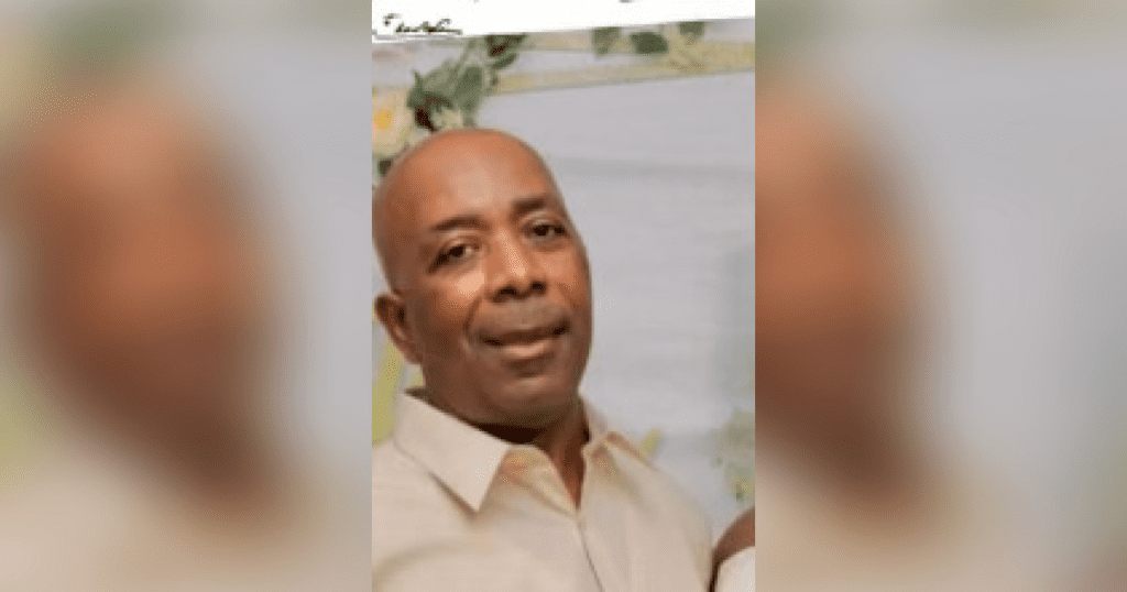 Man smiling in light-colored shirt.