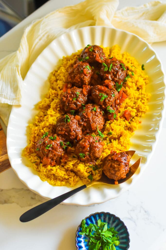 Juicy Braised Lamb Meatballs with Harissa Sauce the best saucy lamb meatballs on a bed of yellow rice sprinkled with fresh parsley.