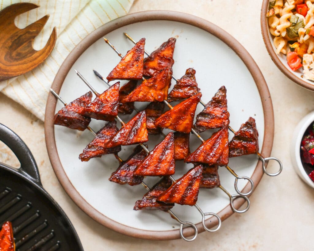 Grilled skewered tofu triangles on plate.