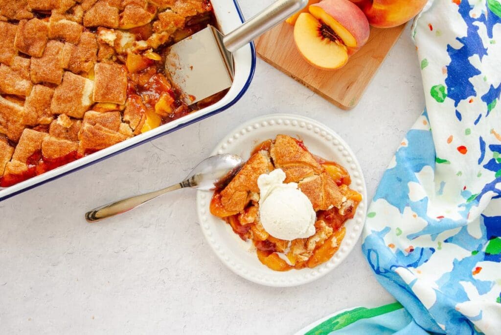 Peach cobbler with ice cream on plate.
